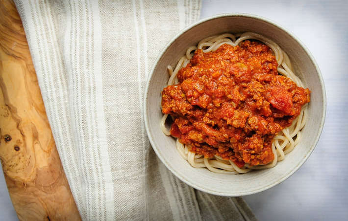 a bowl of spaghetti topped with homemade both broth bolognese