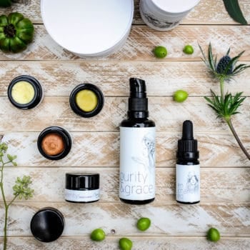 bottles of skincare styled on a wooden background with herbs and greens