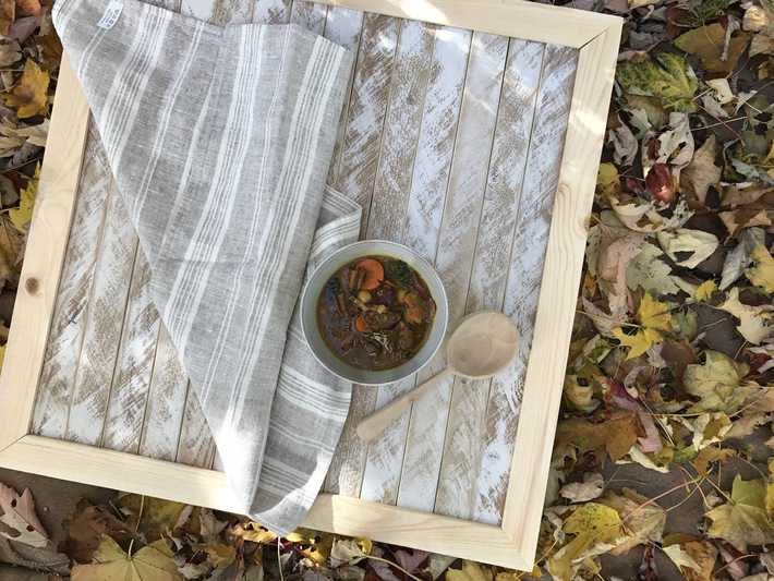 a bowl of homemade kale soup styled on a board outside in the fall