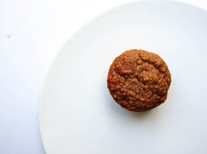 one mini pumpkin muffin on a white plate 