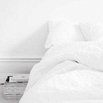 a white bed on the floor with white sheets in a white room