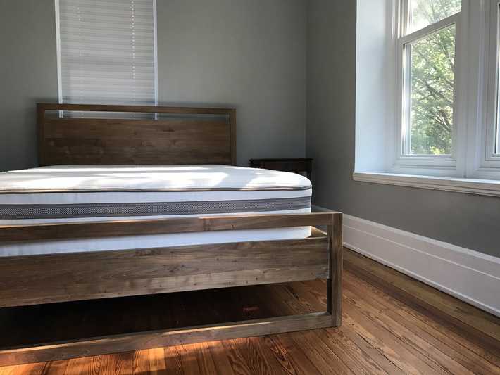 a wooden bed unmade with the mattress exposed 