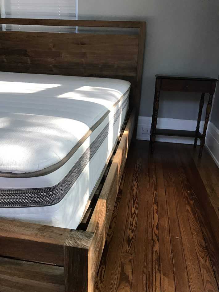 a wooden bed unmade with the mattress exposed 