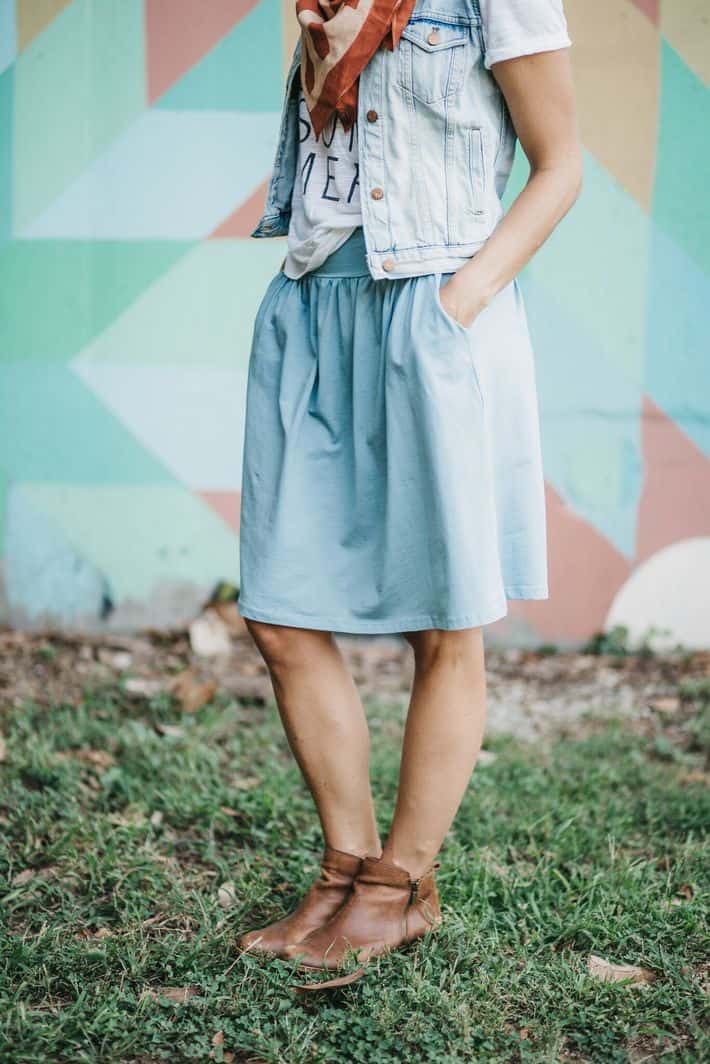 wearing a long periwinkle blue midi skirt with pleats in the front 