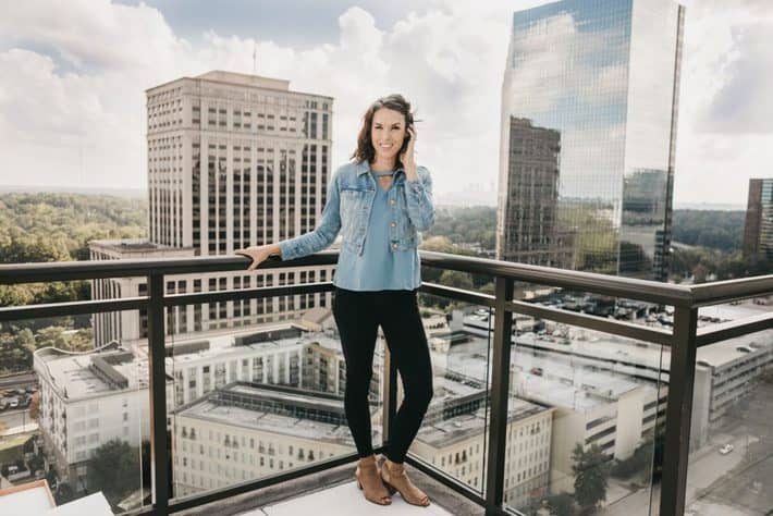 a woman standing on a city rooftop with the city skyline behind her