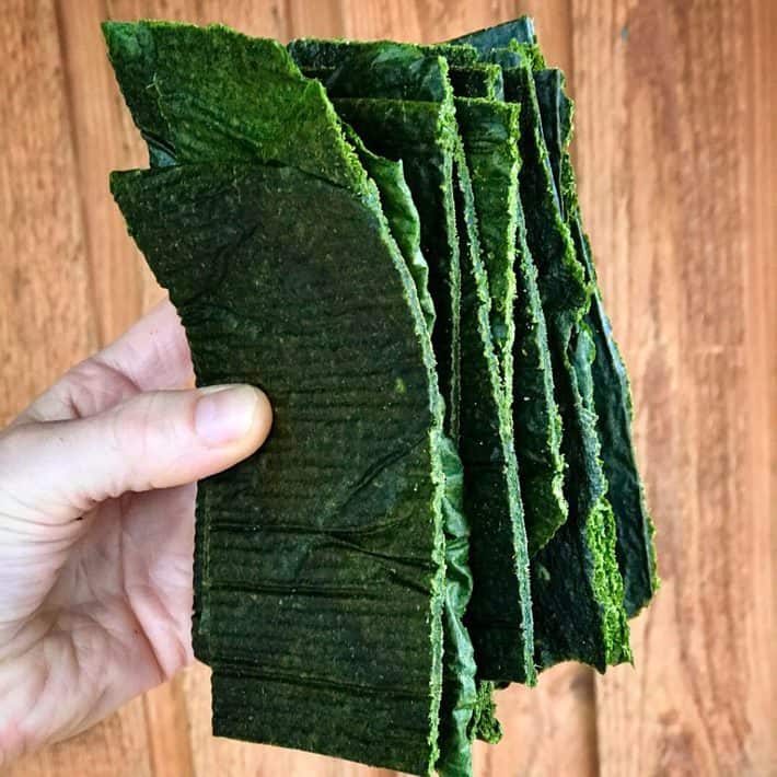 holding a stack of green raw veggie bread cut in strips 