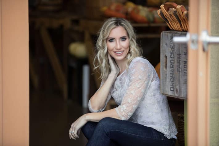 Deanna Mutzel, creator of Real Food Lab, sitting in a rustic barn or kitchen 