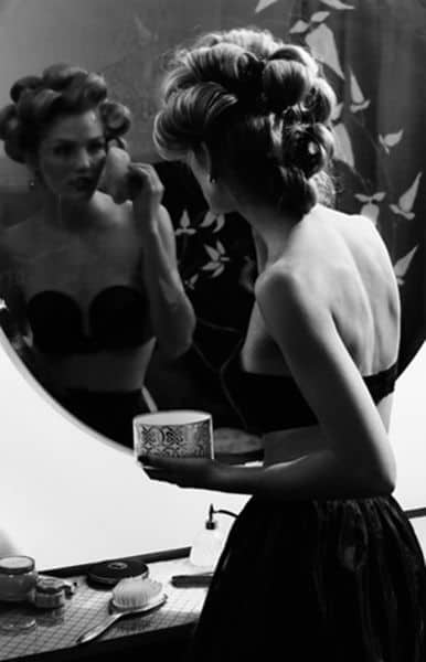 Black and white photo of a girl putting on makeup and getting ready to go out