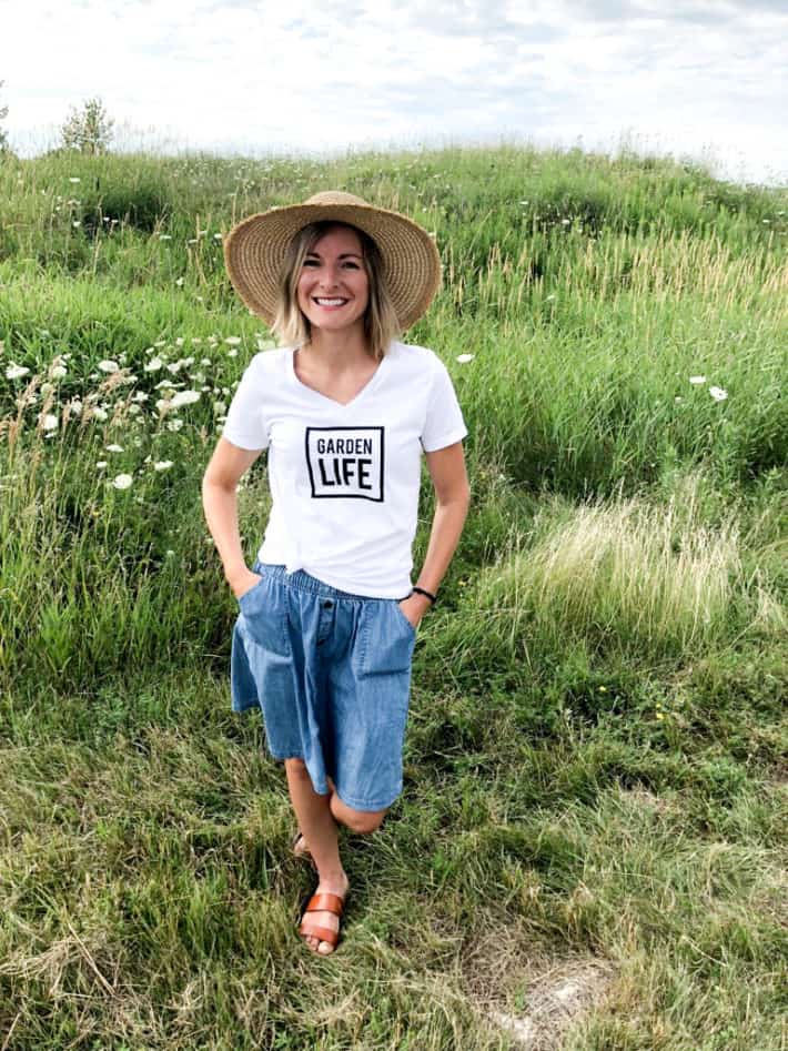 standing in a field wearing a wide brimmed hat and organic gardening tee