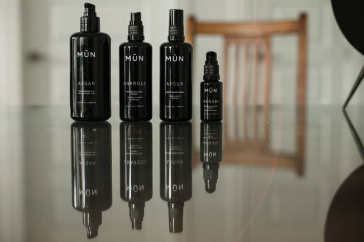 4 bottles of MŪN organic skincare lined up on a mirrored table