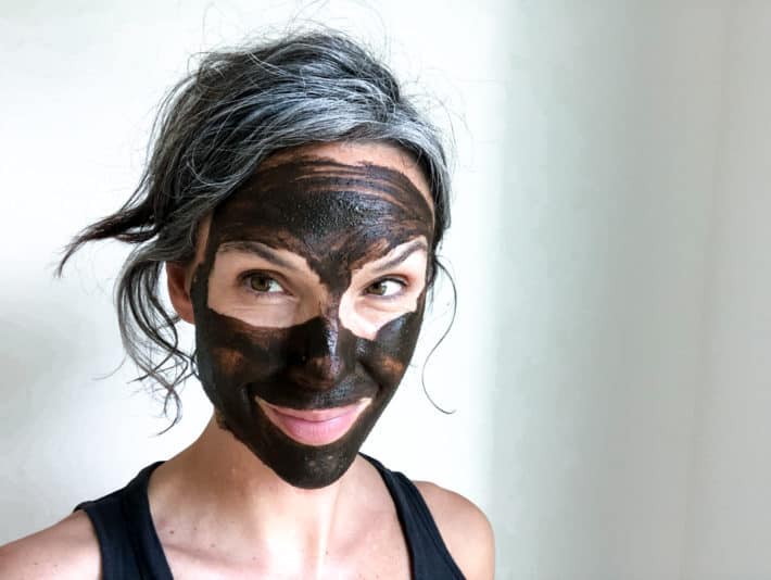 wearing a dark brown mud mask all over face 