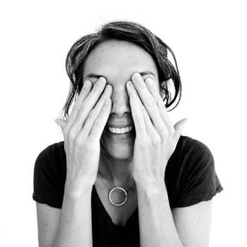 black and white photo of woman smiling and covering her eyes