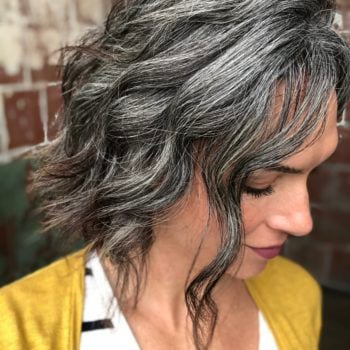Photo of a woman who is growing her hair out to be gray. This photo shows what the hair color looks like 18 months into the graying process