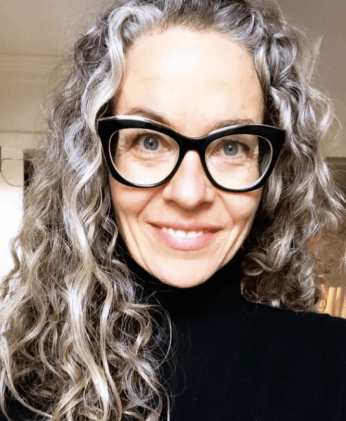 A smiling woman with gray curly hair.