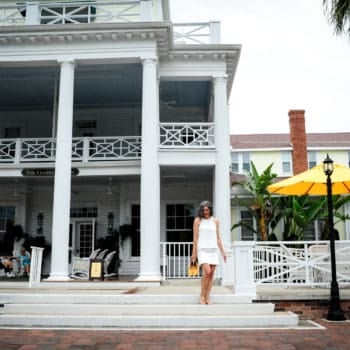 girl wearing a white shirt and white skirt and yellow shoes in front of a souther plantation