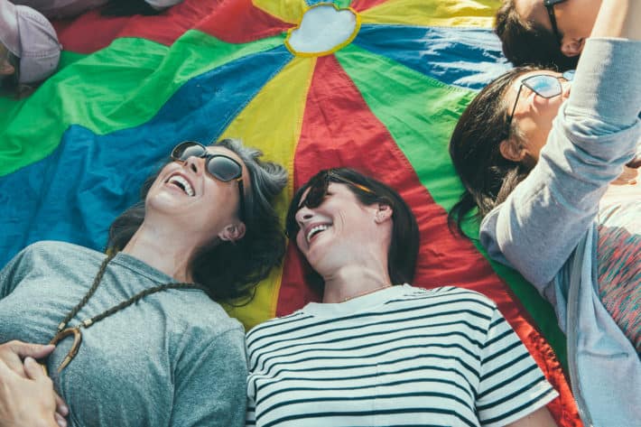 girlfriends laughing and laying on a parachute 