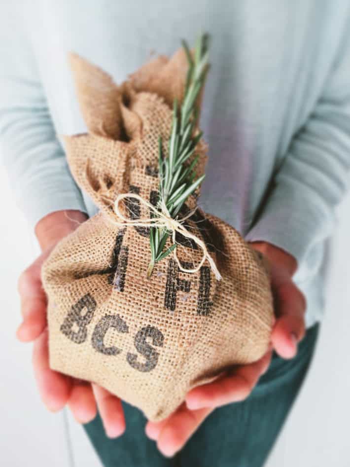 small gift wrapped in printed burlap and greenery