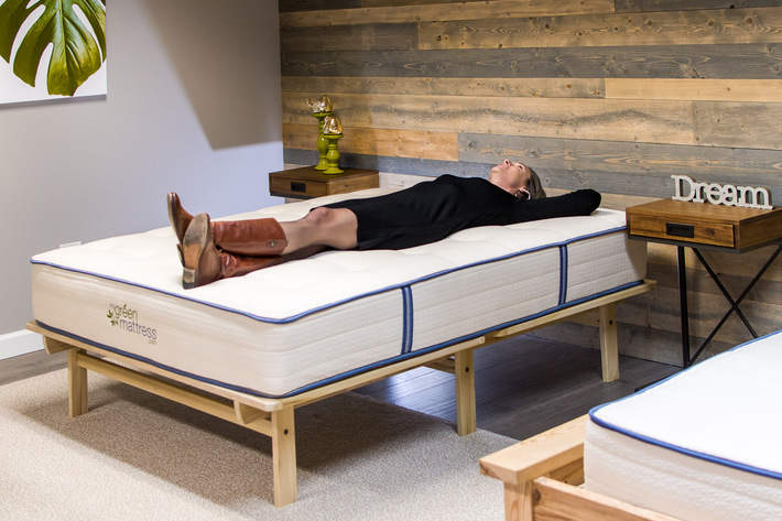A woman laying down on a mattress in the My Green Mattress showroom