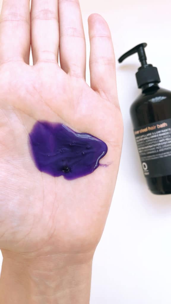 A large drop of OWAY Silver Steel Hair Bath purple shampoo in the palm of a hand