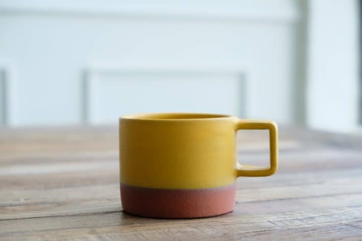 yellow and brown mug placed on a wooden table