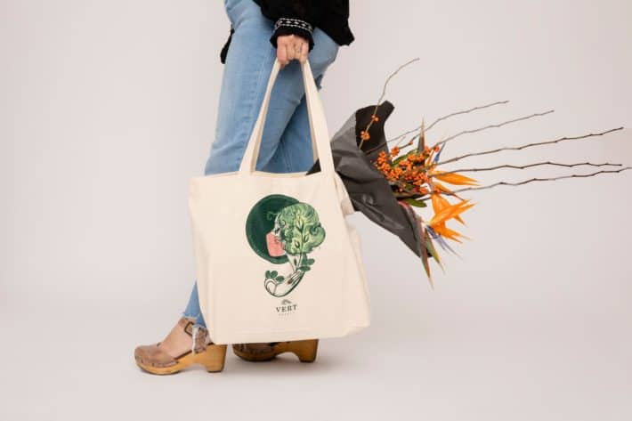 woman holding Vert Beauty tote with fall flowers in the tote