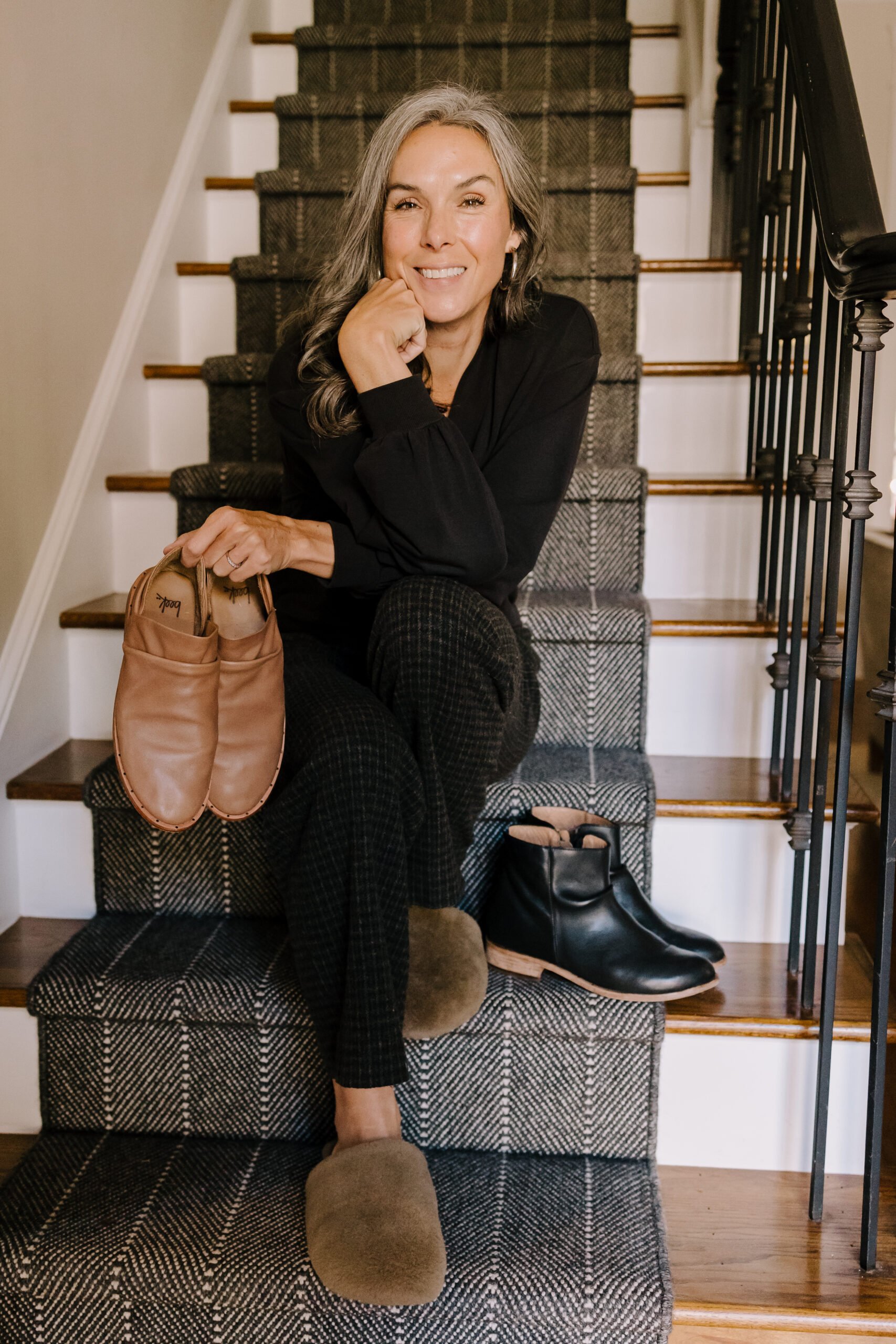 A woman sitting on her stairs holding beek shoes.