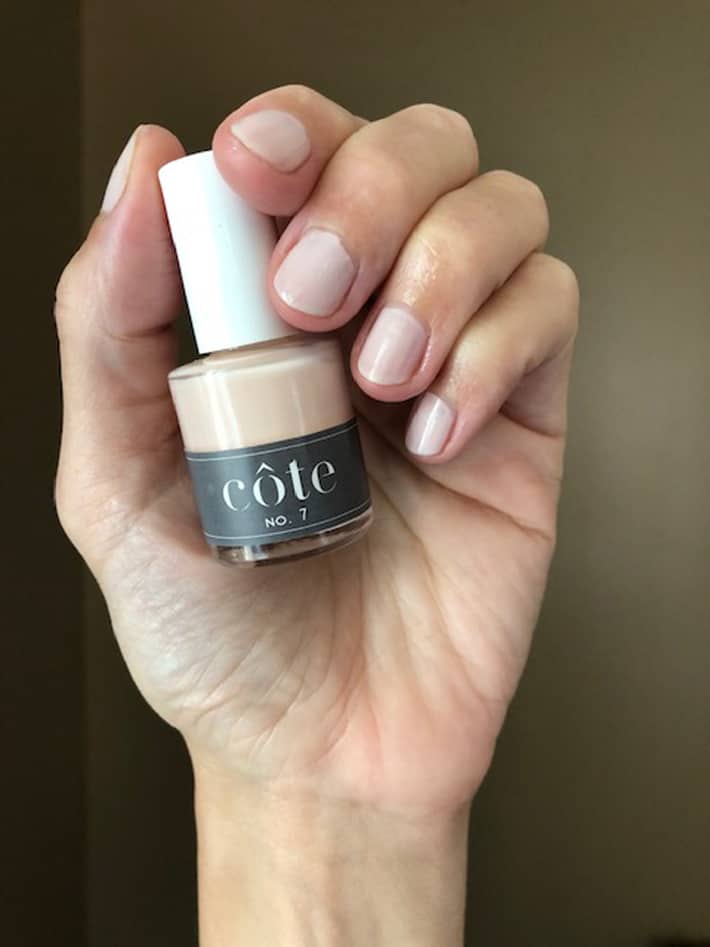 Hand holding Cote Nail polish in No. 7, a neutral almond shade.