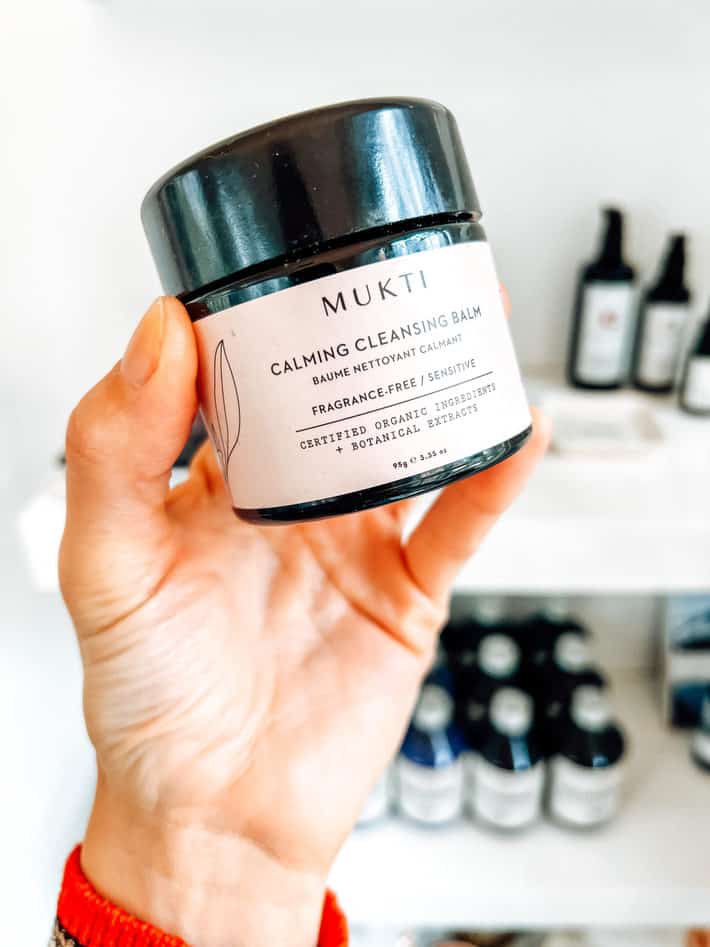 Holding a jar of cleanser from Mukti