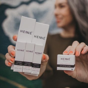 Lisa holding boxes of Henne Organics lip balm, luxury lip tints and lip exfoliator
