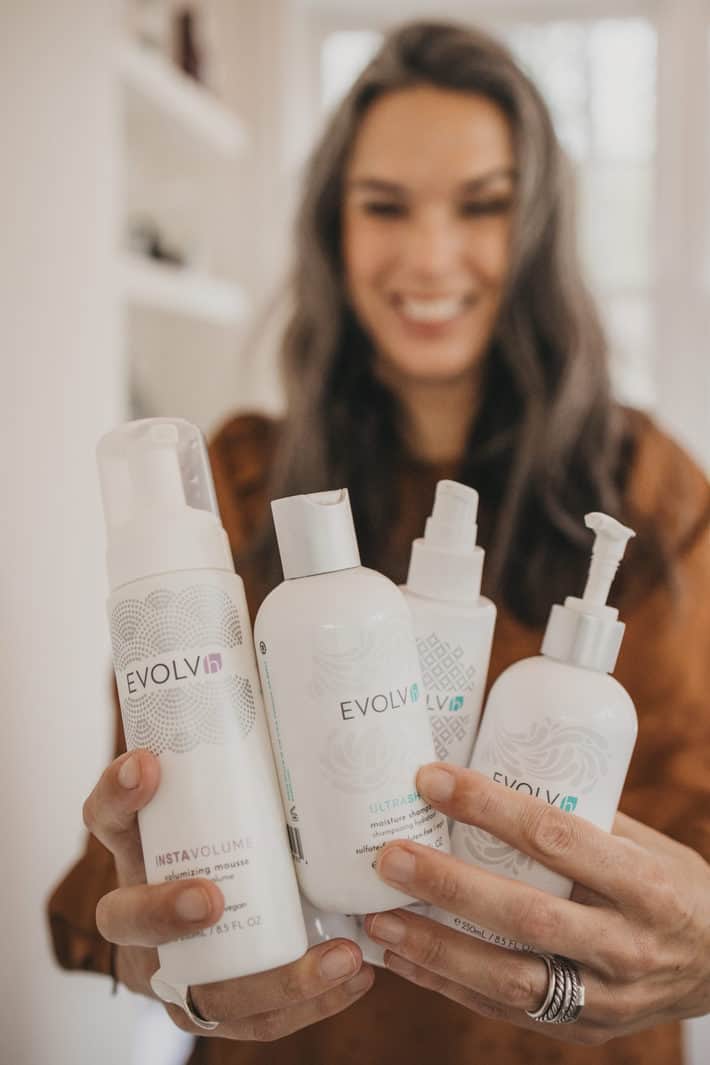 lisa holding EVOLVh shampoo and conditioner and volumizing mousse