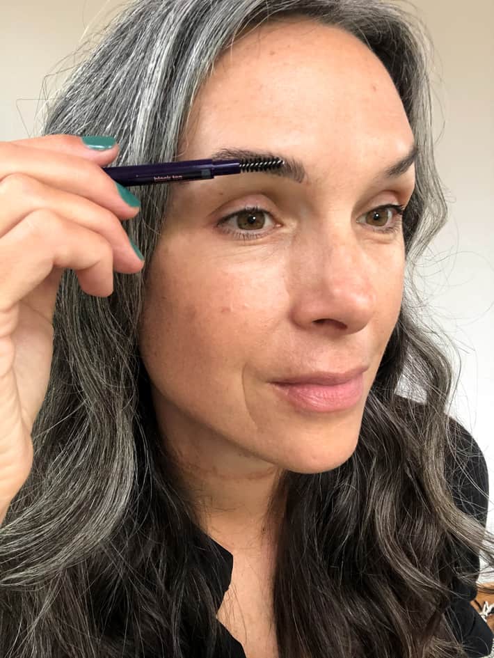 lisa buffing out brow filler with spoolie for a natural look
