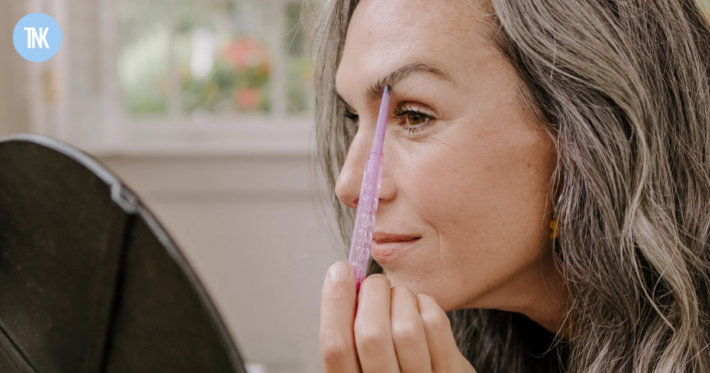 A woman applies eye brow makeup to her brows.