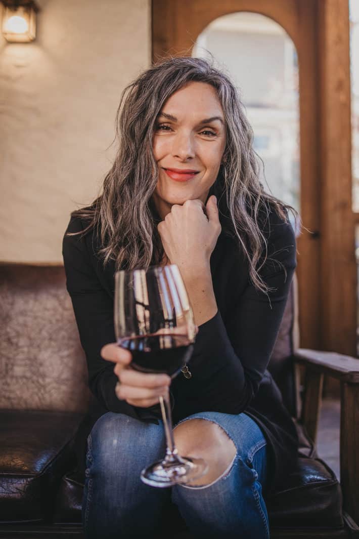 A woman holds a glass of dry farm wines wine. 