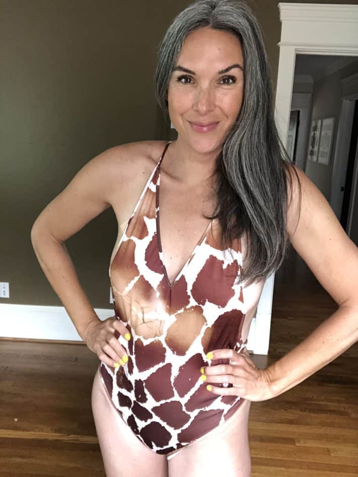 Lisa wearing a giraffe print one-piece swimsuit with her hands on her hips.