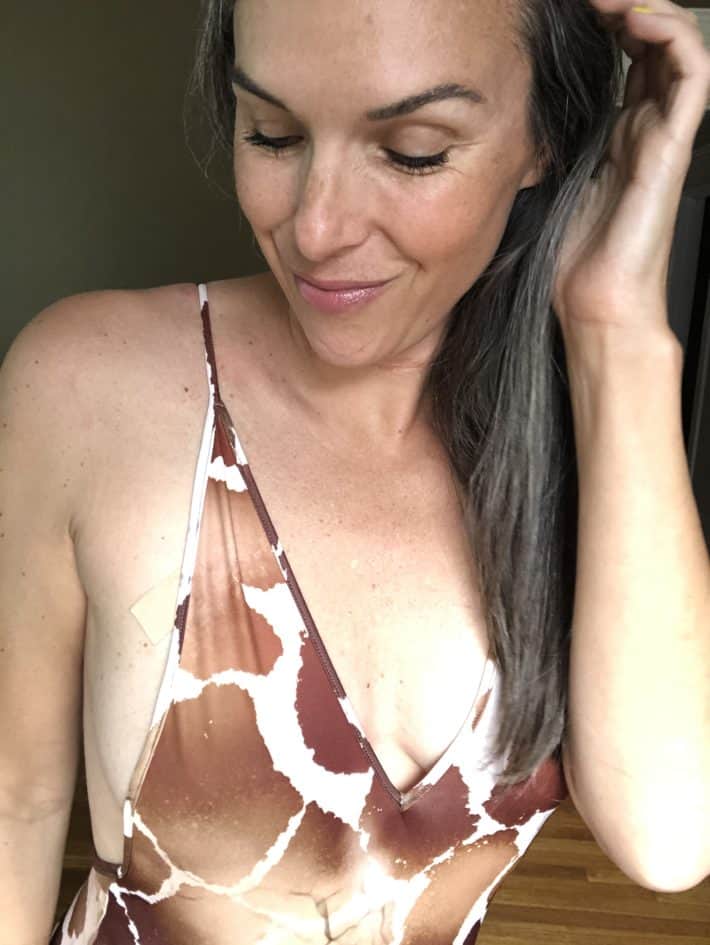 Lisa wearing a giraffe print one-piece swimsuit in a close up of her face.