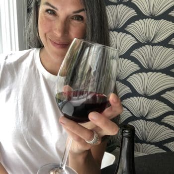 Lisa smiling and holding a glass of red wine.