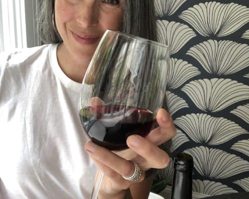 Lisa smiling and holding a glass of red wine.