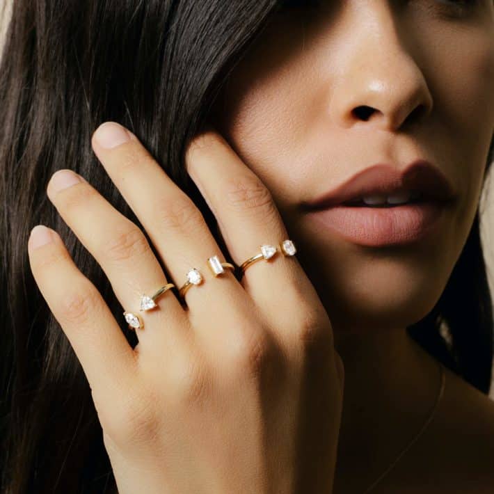 woman with dark hair wearing rings on all fingers