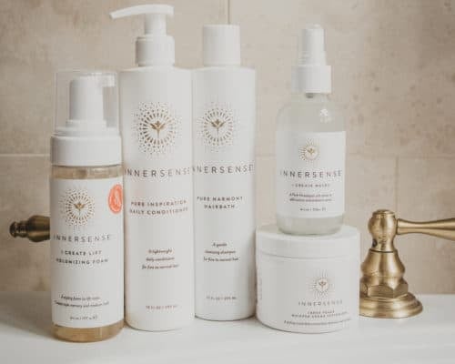 A stacked collection of Innersense hair products sits on a white bathroom sink.