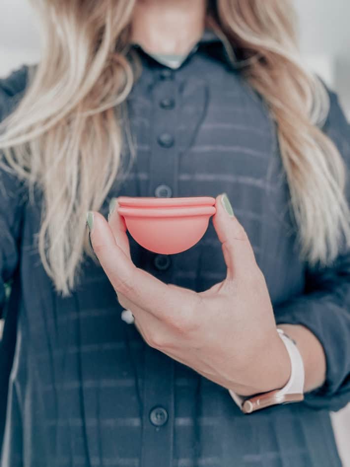 woman holding a pink reusable period cup