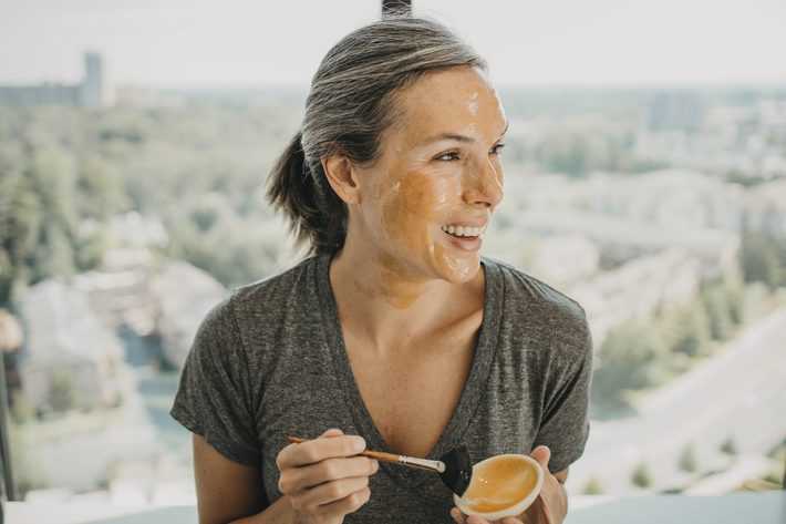 woman applying honey mask on her face