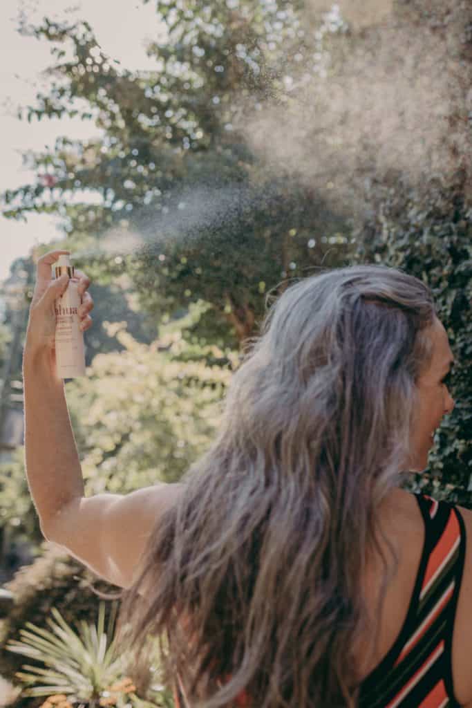 woman spraying spf on hair