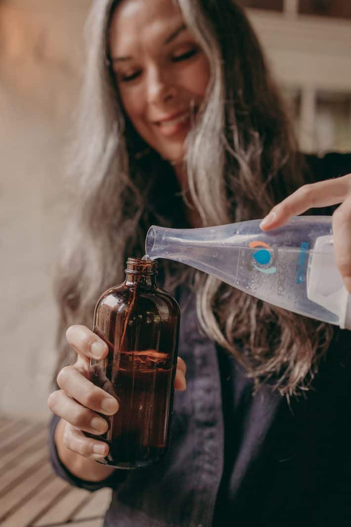 woman pouring cleaner mix into bottle