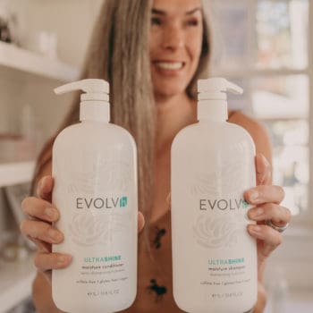 lisa holds two liter bottles of clean shampoo and conditioner from EVOLVh