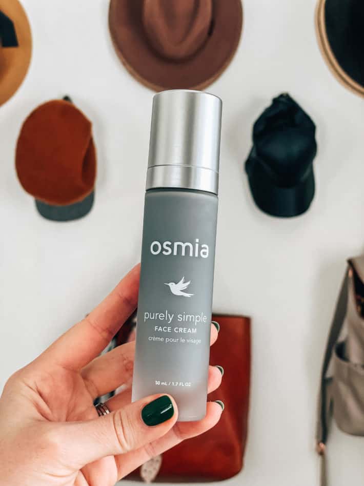 a hand holds up osmia organic purely simple face cream