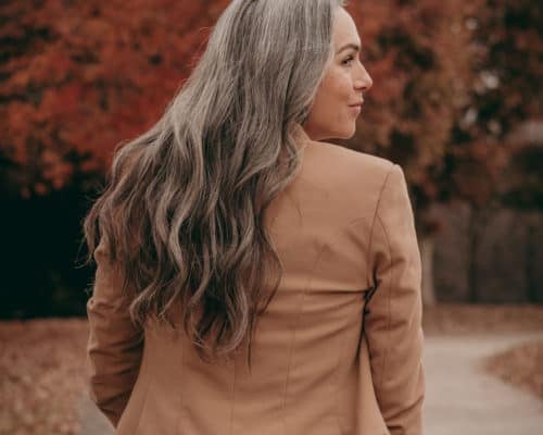 woman with gray long wavy hair in nude jacket