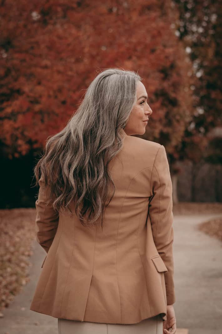 woman with gray long wavy hair in nude jacket