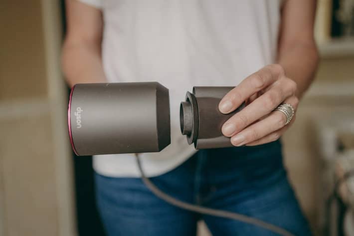 woman holding an attachment from Dyson and the Dyson hair dryer 