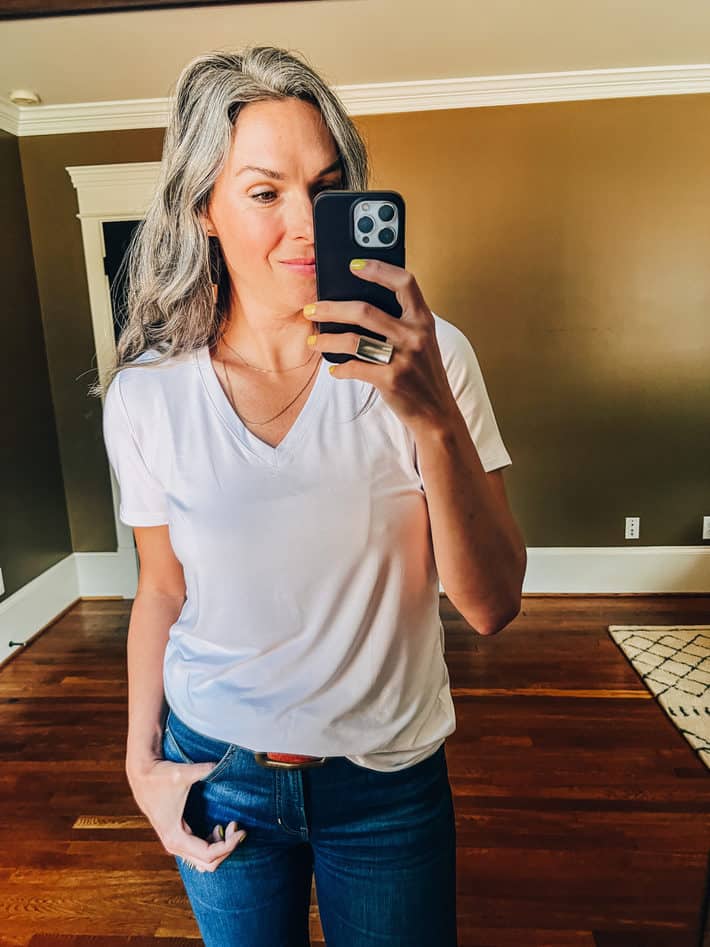 Lisa wears a white tshirt taking a selfie in the mirror.