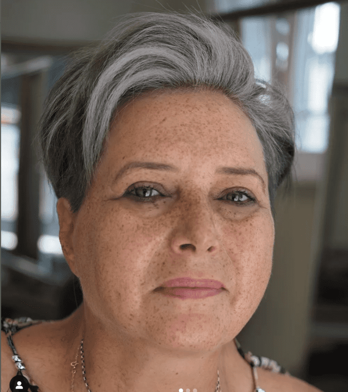 woman with freckles and short gray hair looks at the camera